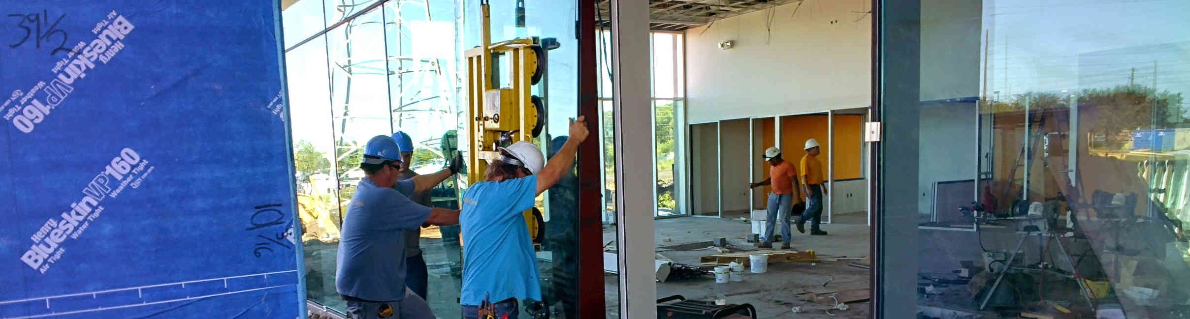 A crew installing large glass panels into a curtain wall system that we designed and engineered.